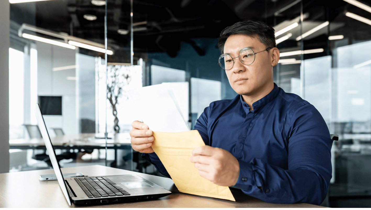 Man reading documents in front of a laptop 